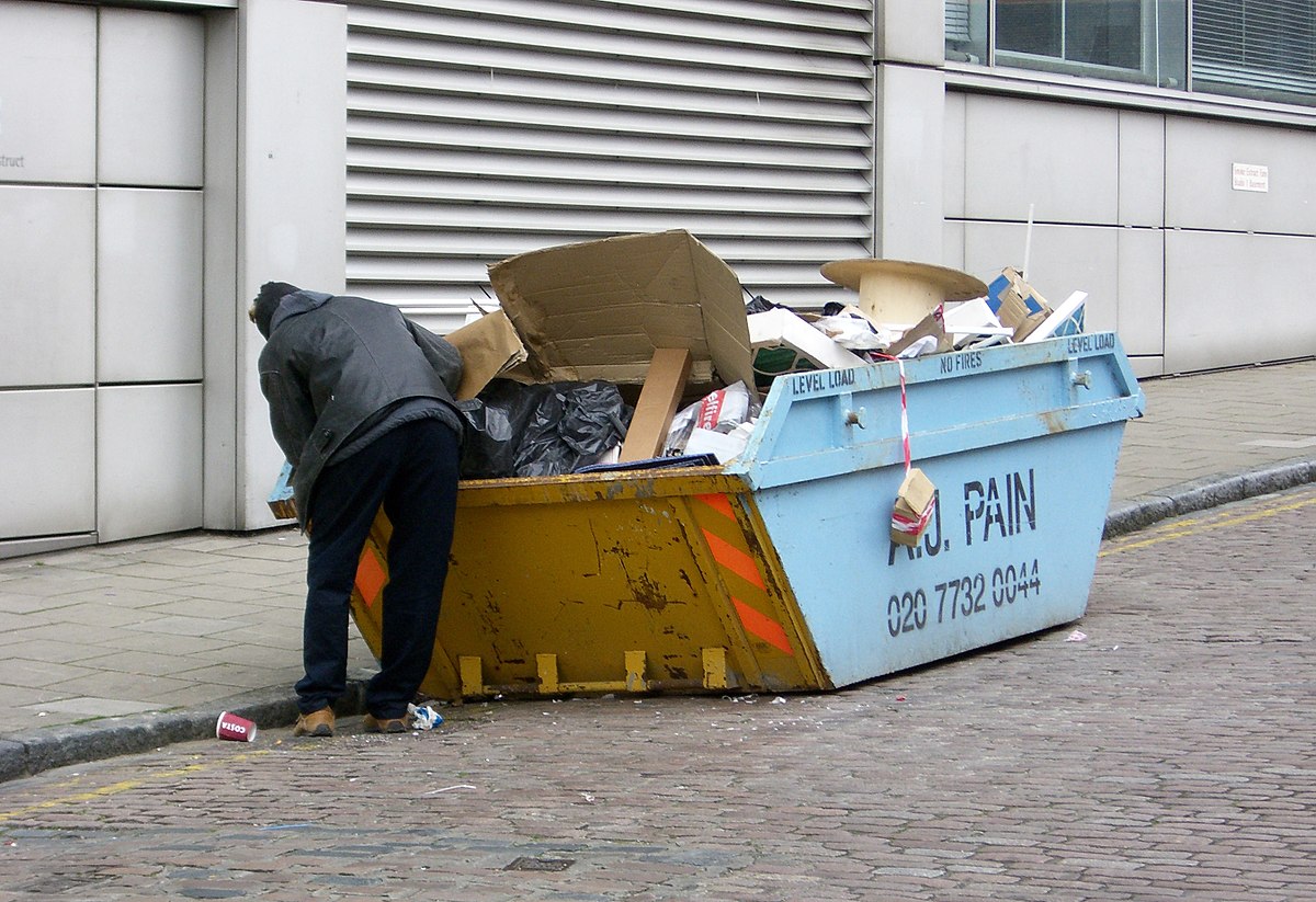 Benne à ordures à Londres, fouillée par une personne pauvre y récupérant des déchets réutilisables.