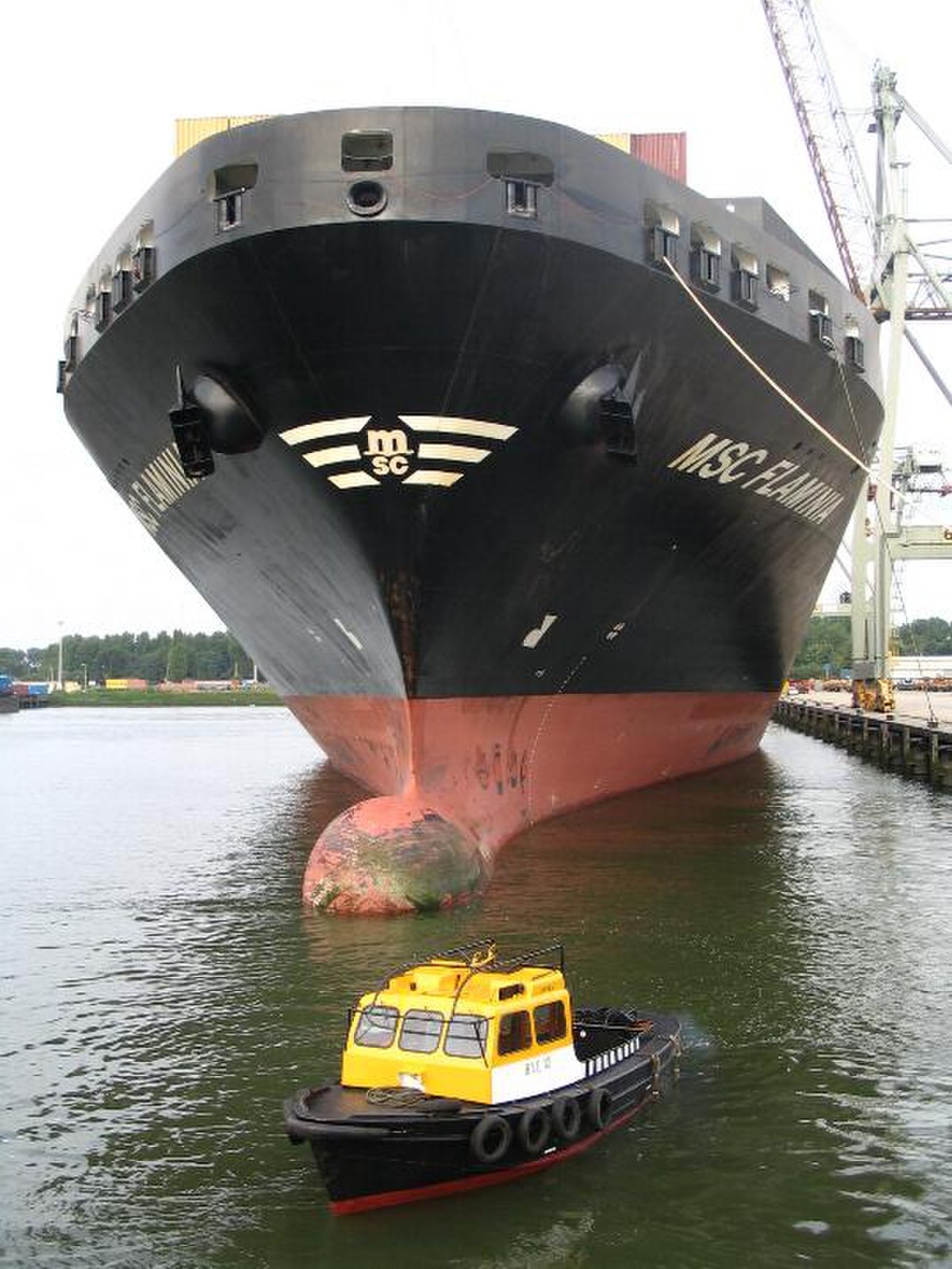 Bateau de lamanage devant la proue d'un porte-conteneurs.