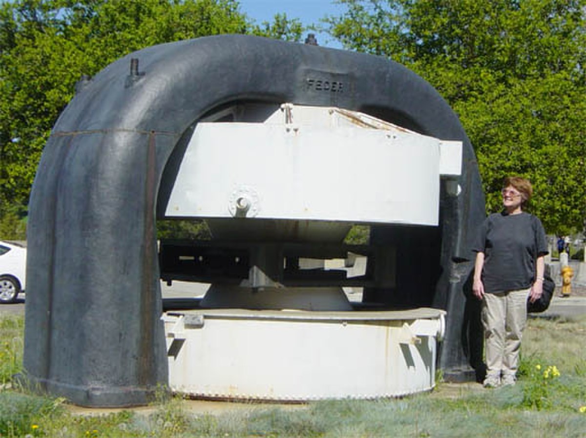 Un électro-aimant de cyclotron au Laurence Hall of Science. Les parties noires sont en acier et se prolongent sous terre. Les bobines de l'aimant sont situées dans les cylindres blancs. La chambre à vide se situerait dans l’espace horizontal entre les pôles de l'aimant.