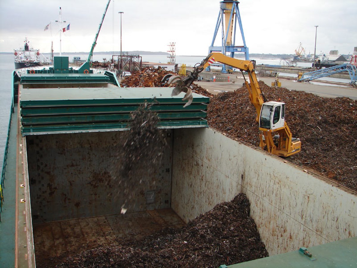 Chargement de ferraille à travers l'écoutille d'un vraquier côtier.